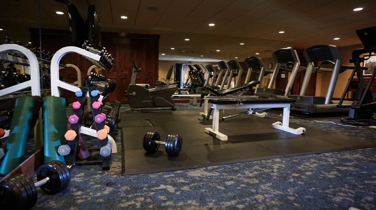 A modern fitness center equipped with treadmills, dumbbells, and a weight bench, offering an energetic and welcoming space for workouts and wellness routines.