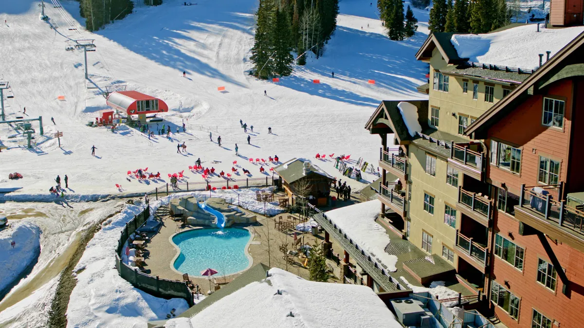 A vibrant exterior shot capturing the ski slopes, an inviting swimming pool, ski lift, lodge buildings, and people both skiing and relaxing. The image blends the excitement of winter sports with the comfort of resort amenities, showcasing the unique ski-in/ski-out lifestyle.
