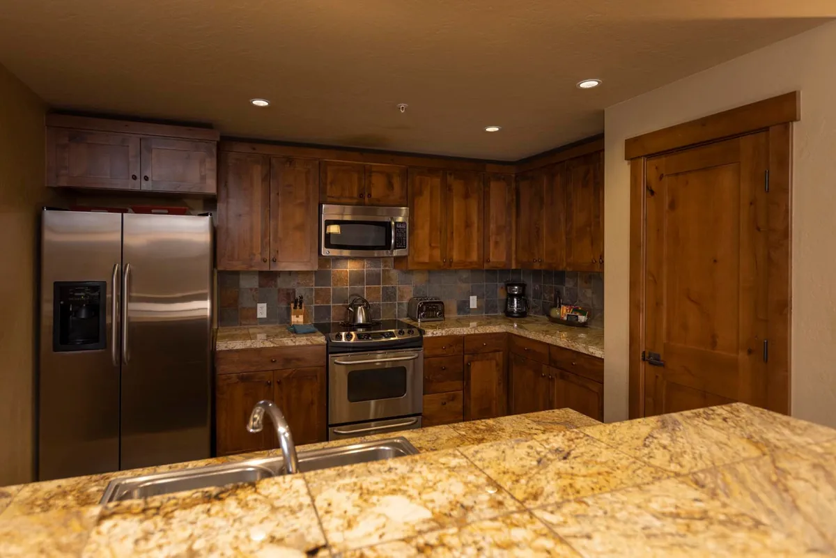 A stylish and cozy kitchen interior featuring granite countertops, stainless steel appliances, and warm wooden cabinetry. The space is designed for entertaining, family gatherings, and enjoying meals together in an upscale environment.